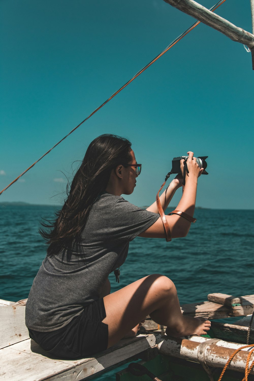 woman sitting beside boat while holding DSLR camera