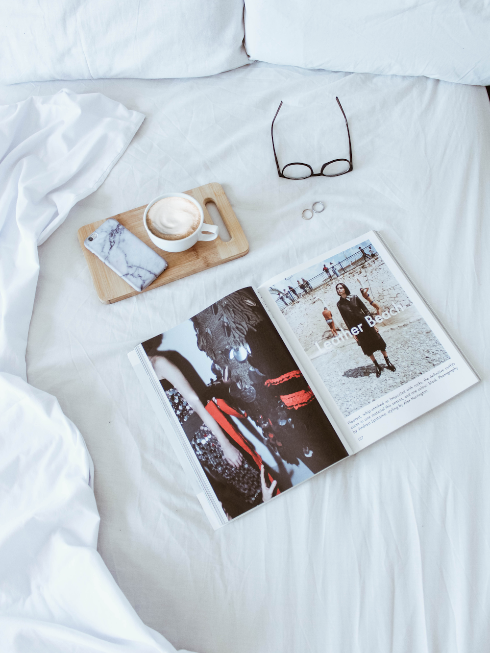 leather beach magazine on top of white comforter