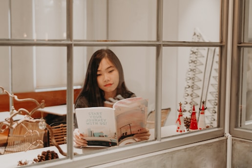 woman reading a book near window