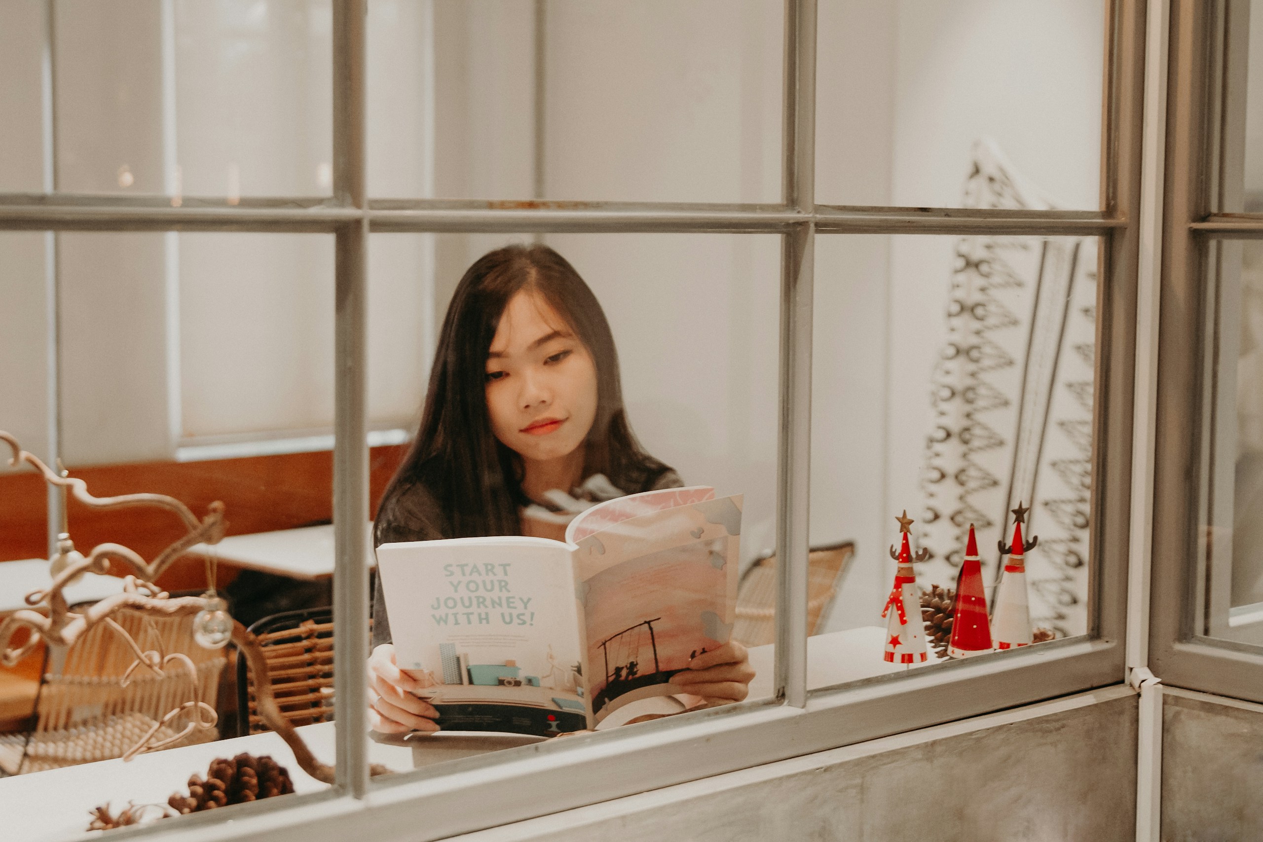 Asian woman reading a book near window
