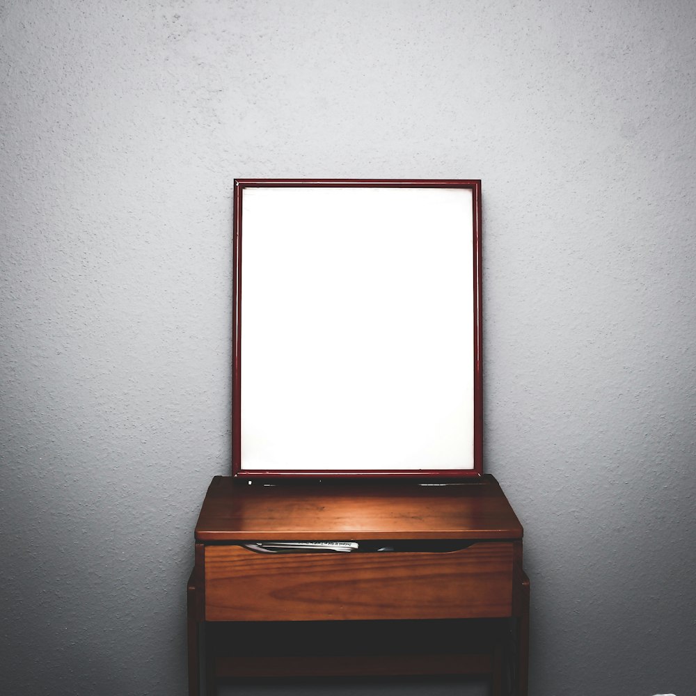 cômoda de madeira marrom com espelho dentro do quarto branco