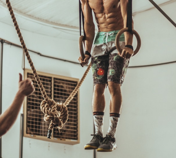 man wearing multicolored shorts while exercising on rope inside white room