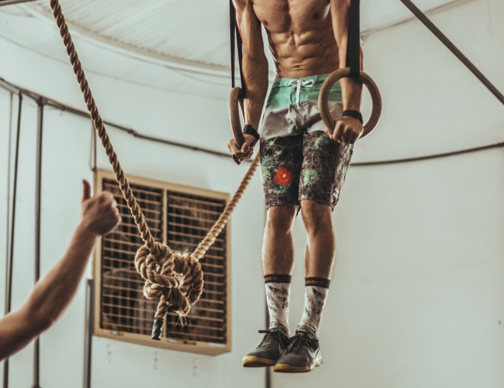 man wearing multicolored shorts while exercising on rope inside white room