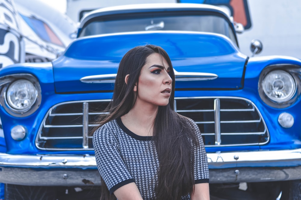 woman sitting beside blue car