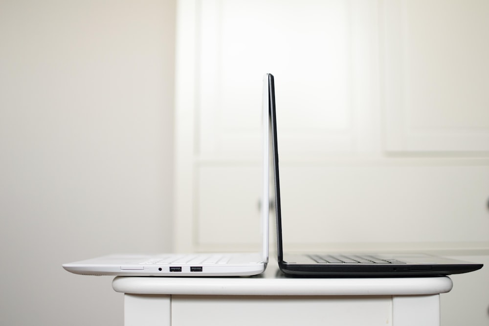 Computadora portátil en blanco y negro sobre la mesa espalda con espalda