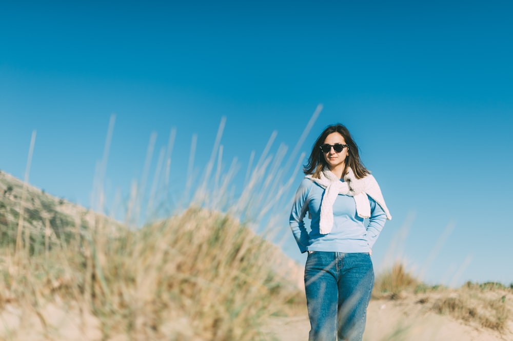 woman wearing blue sweater and blue jeans standing near grass