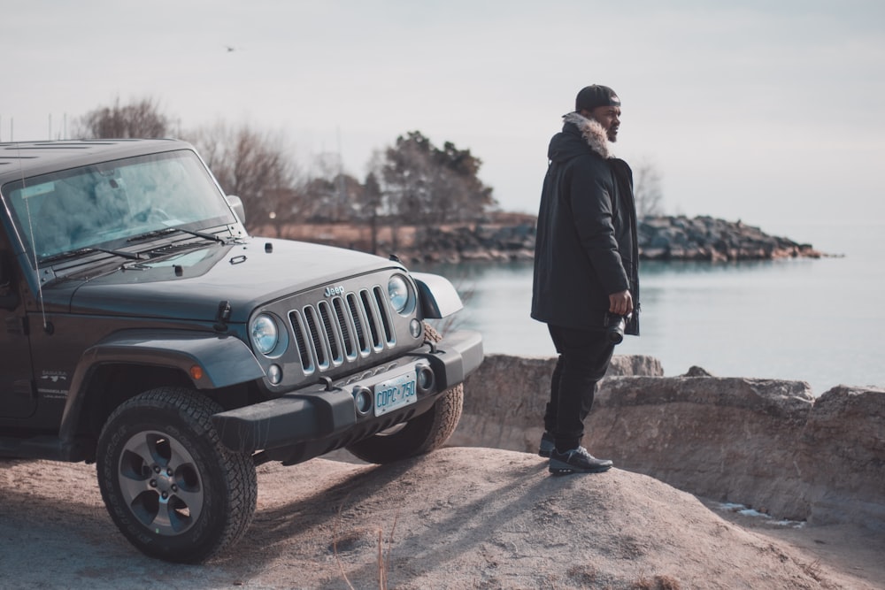 homem na jaqueta preta do parka perto do preto Jeep wrangler