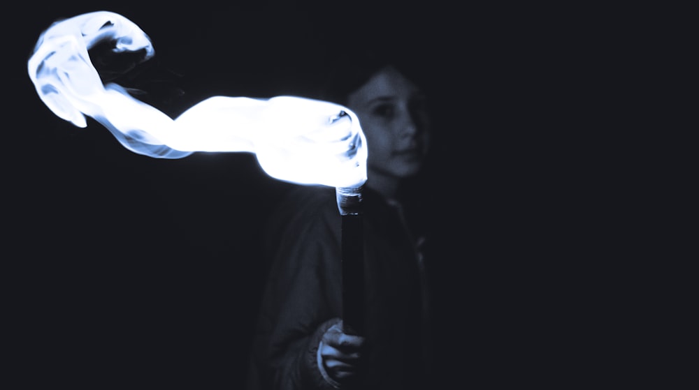 grayscale photo of person holding torch