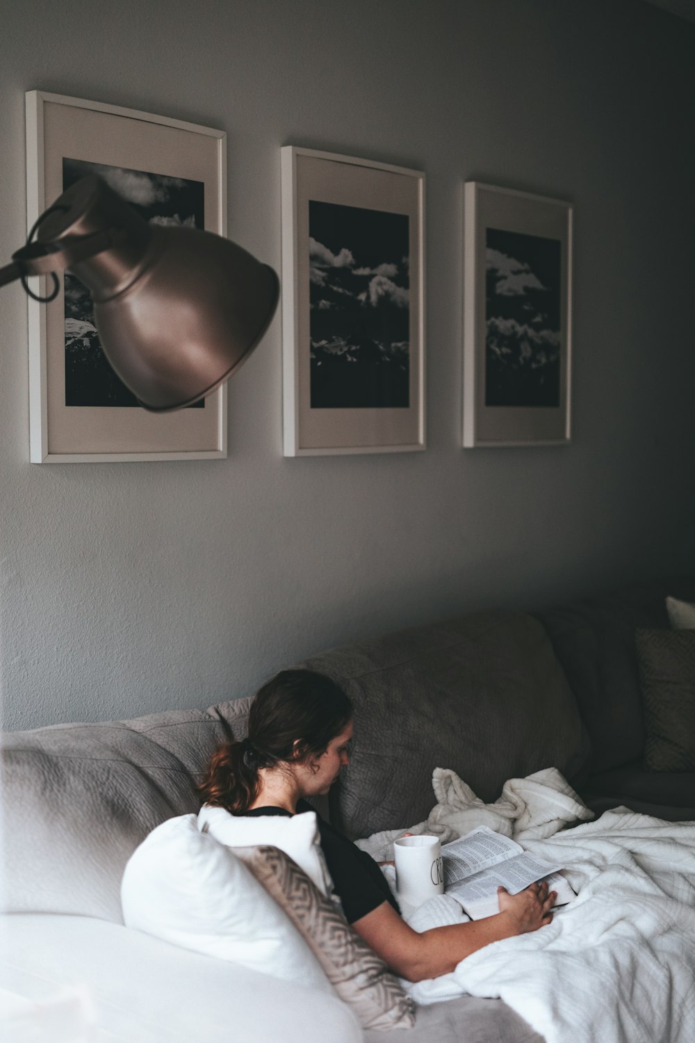 Mujer leyendo libro sentada en sofá gris