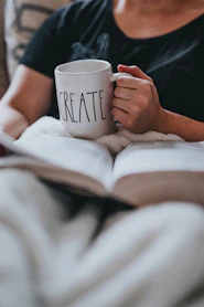 person drinking coffee while reading indoors