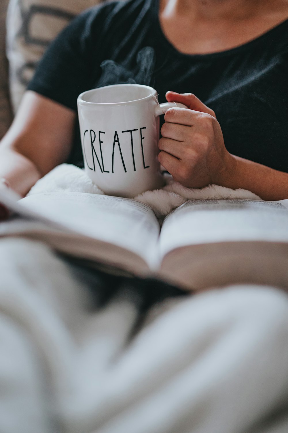 person drinking coffee while reading indoors