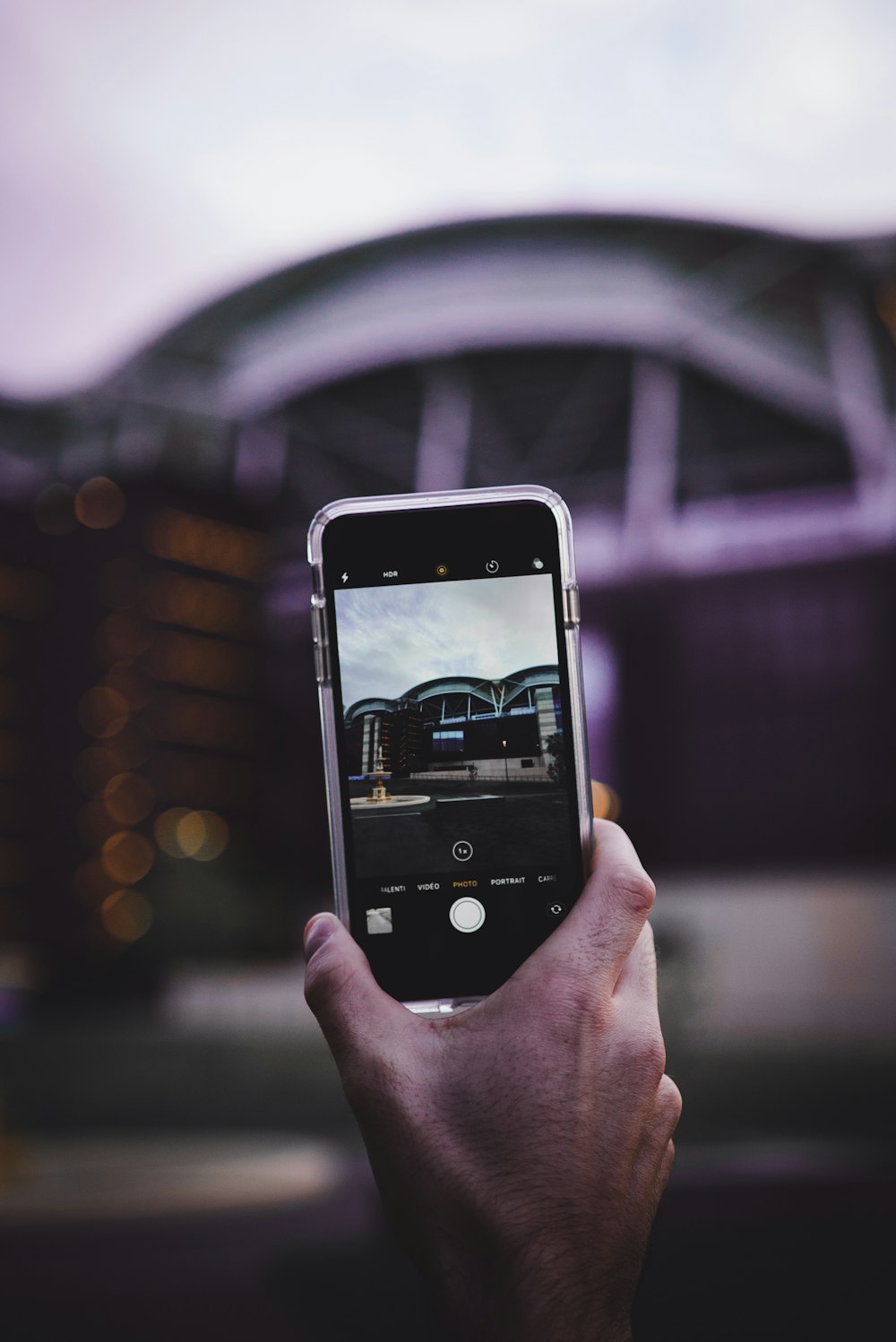 person taking a photo of gray building using phone during daytime