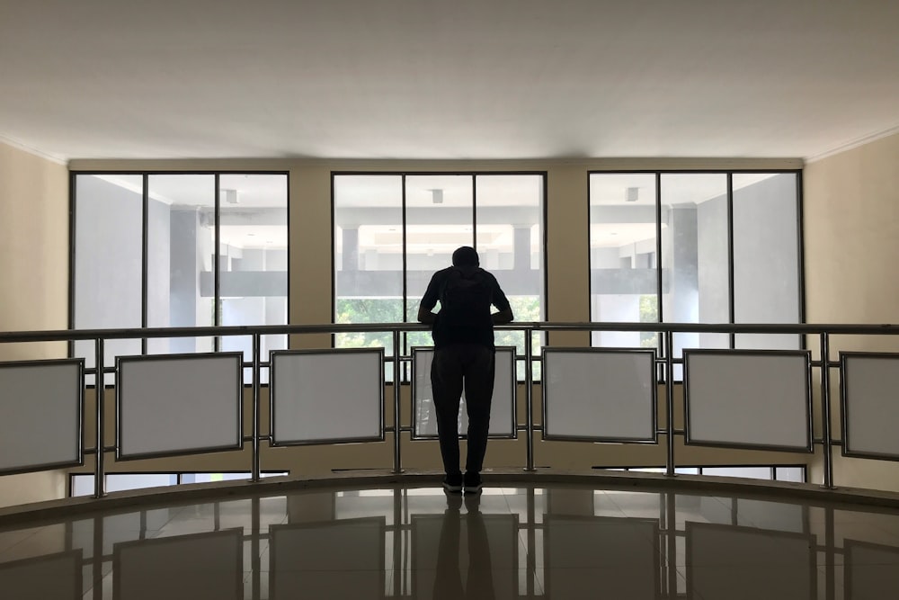 silhouette photography of person standing in front of railing