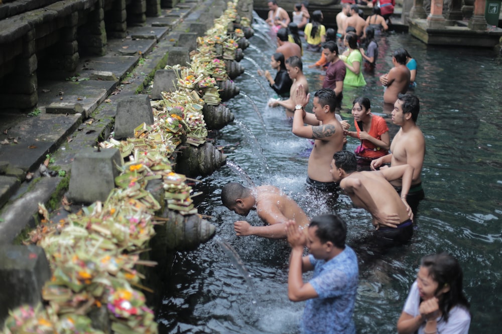 group of people take a bath on fountain during daytime