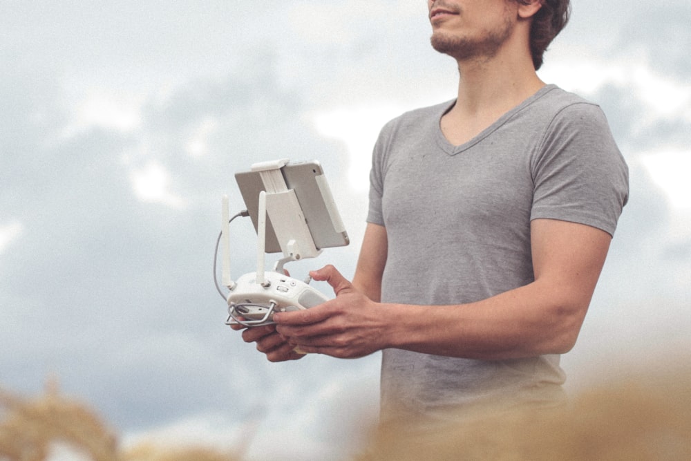 man holding white and gray drone controller