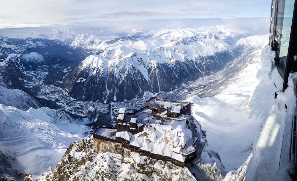 Foto aerea della casa coperta di neve vicino alla montagna della calotta innevata durante il giorno