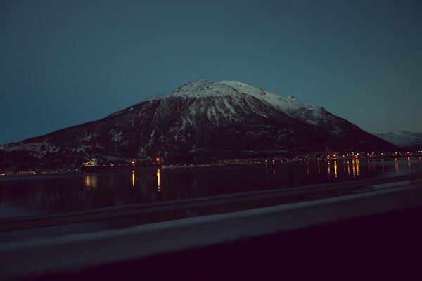 A snowy mountain above the lit shore at night — Narvik, Norway