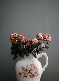 An elegant ceramic bouquet featuring roses and leaves arranged in a rustic vase.