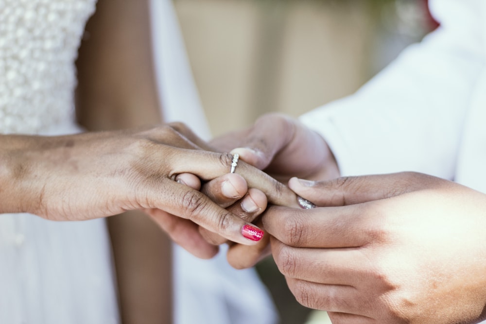 person putting ring on ring finger of woman