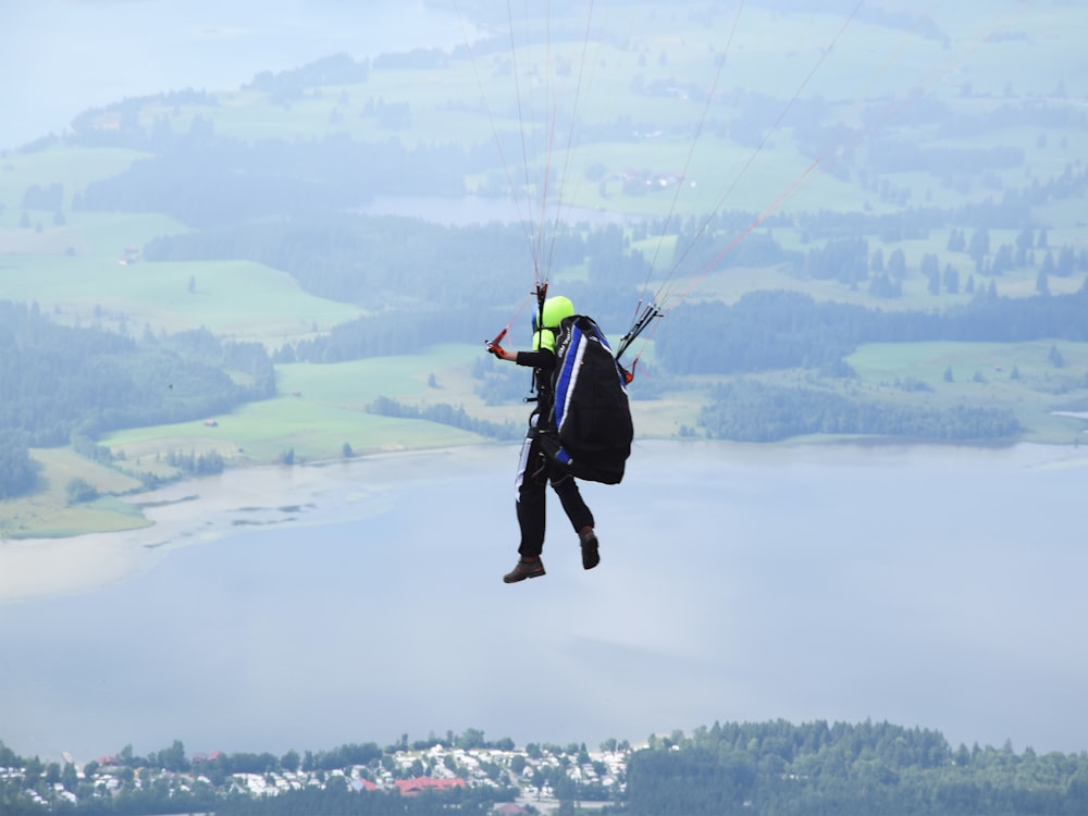 man using parachute above town near water