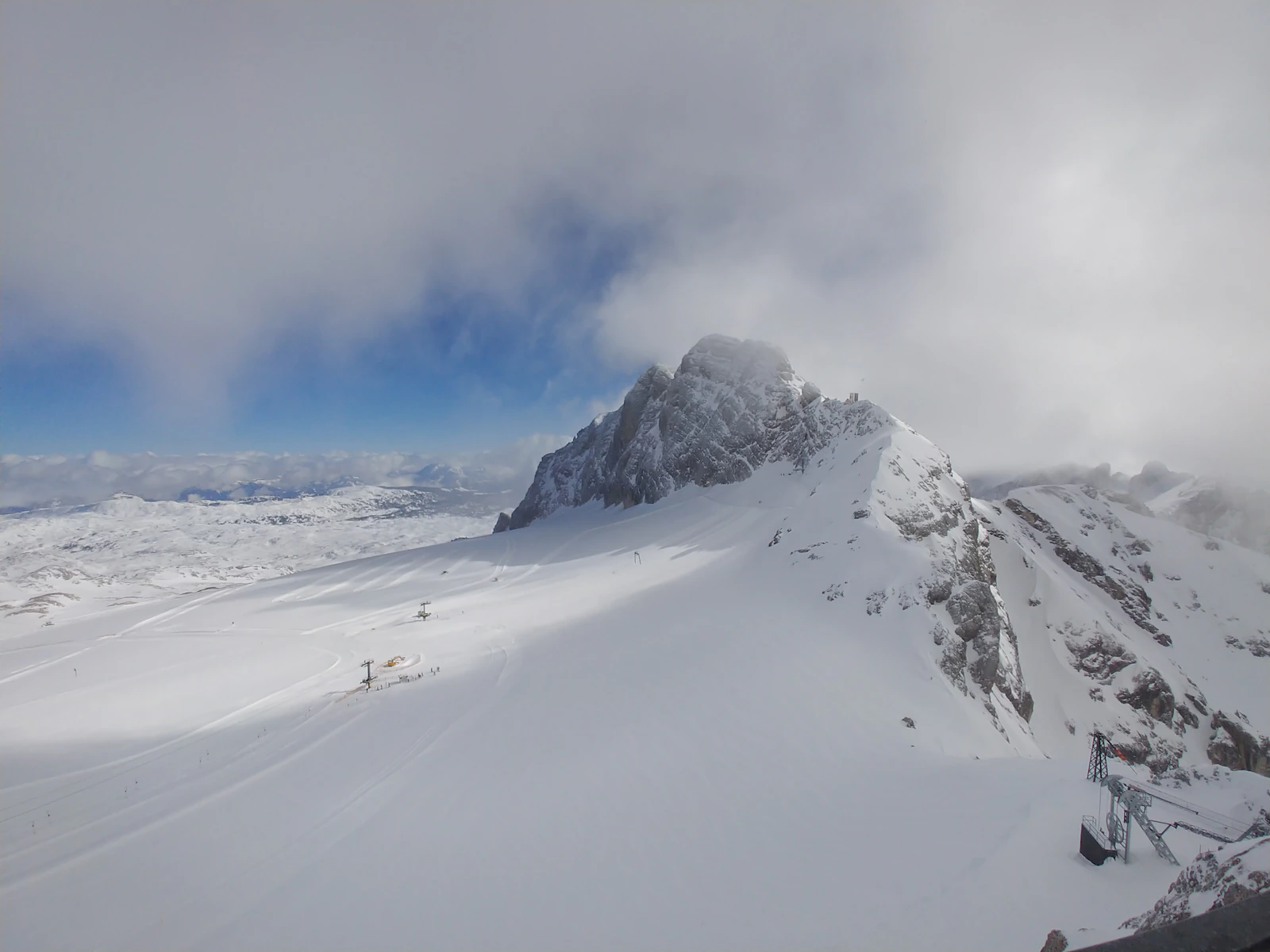 Low cloud covers a snow-covered Alpine village and mountain.