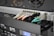 A close-up view of the back of a server rack with multiple network cables connected to a switch. The cables are in different colors including white, orange, black, and light blue. There are also various ports, indicators, and a digital display indicating some operational parameters.