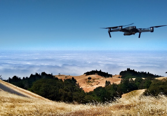 black drone on air over cloudy sky at daytime