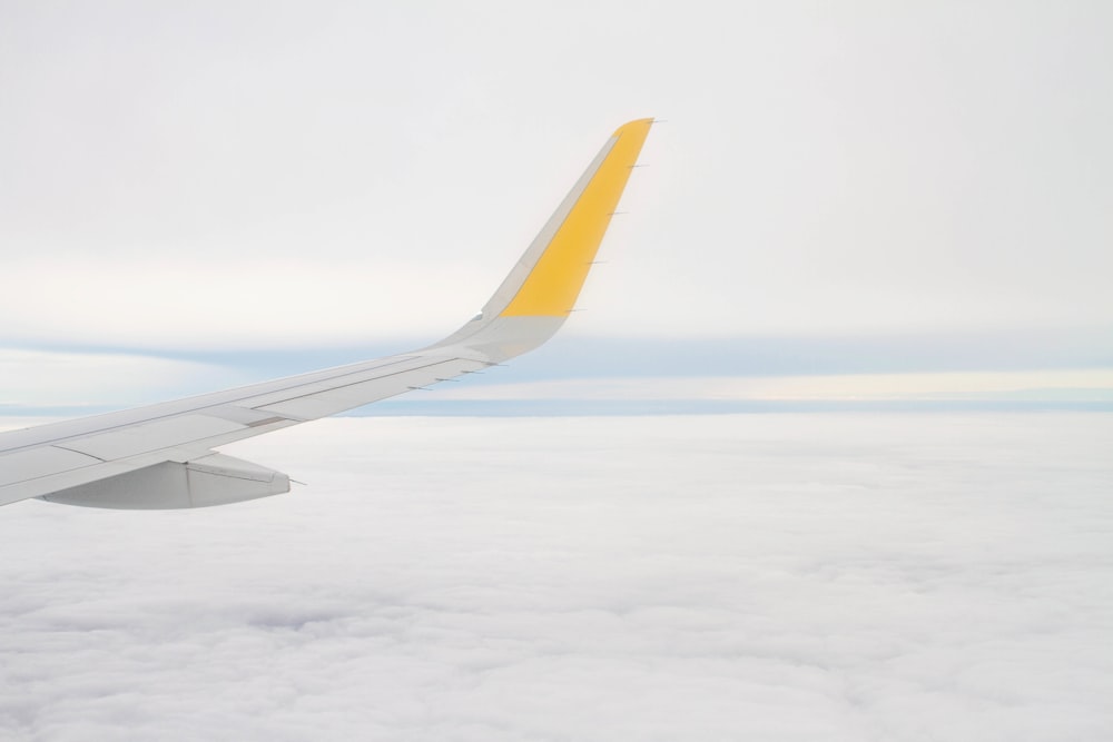 right airplane wing over white clouds during daytime