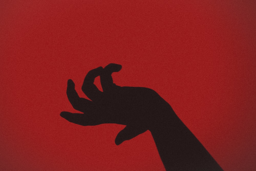 silueta de la mano con fondo rojo