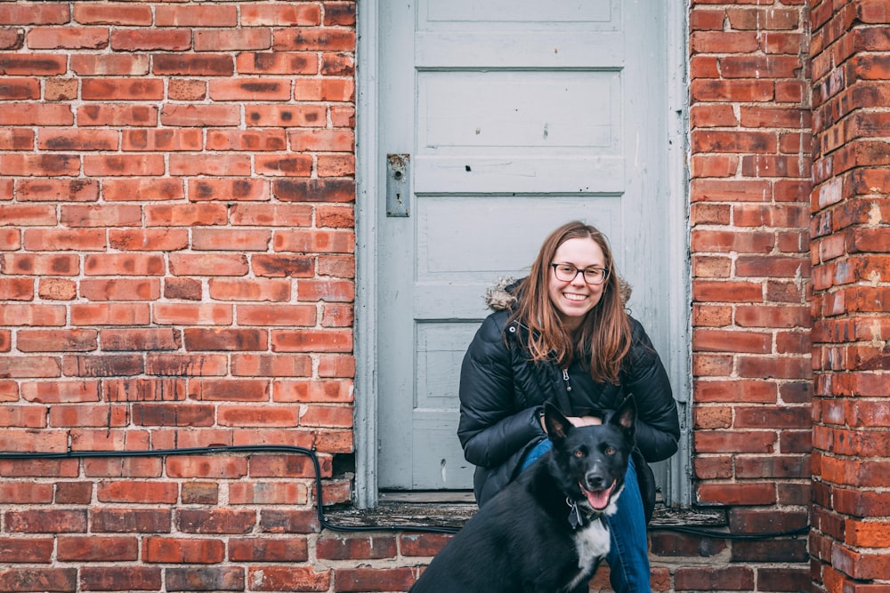 woman sitting outside the house beside dog