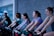 A group of smiling riders mid-spin class, sweat and smiles showing their effort.