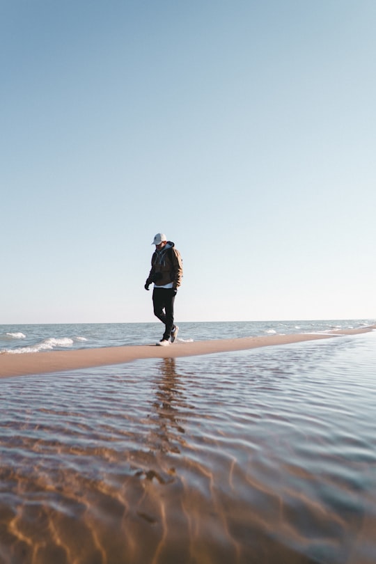 man walks on pathway in middle of body of water during daytime in Kohler-Andrae State Park United States