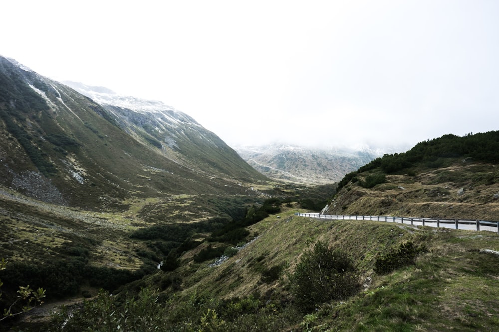 road near mountain under gray sky