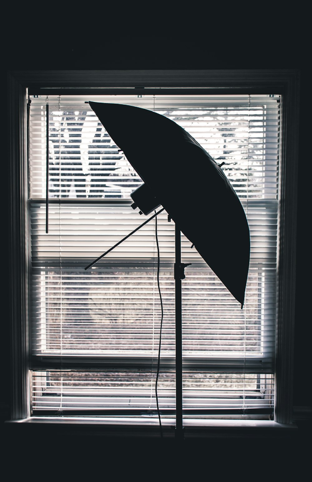 black umbrella near white window blinds