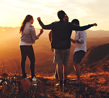 four people standing on edge of mountain