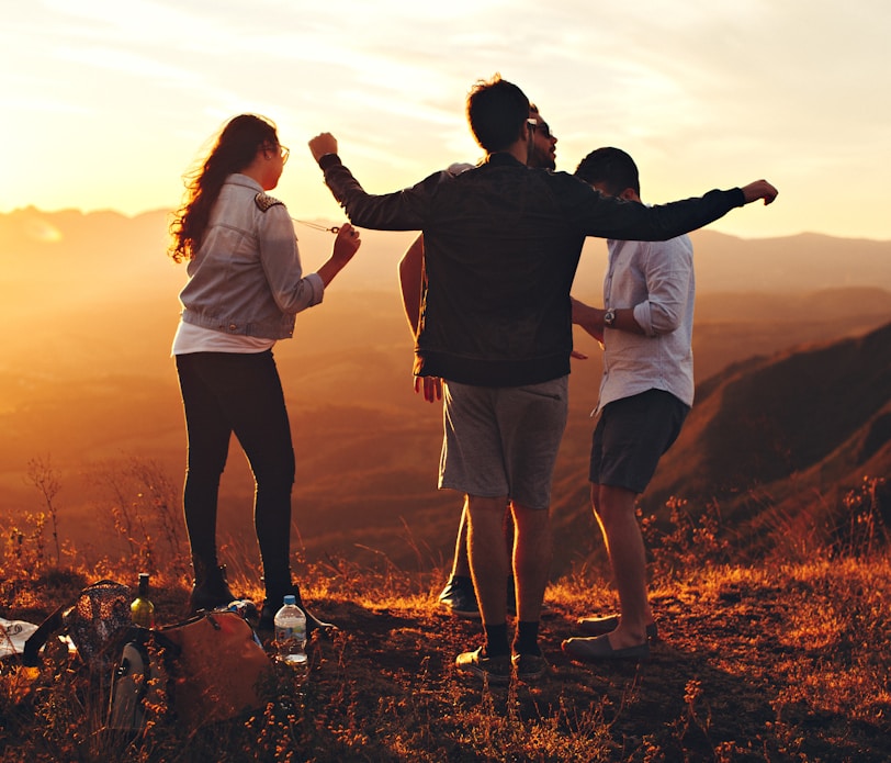 four people standing on edge of mountain