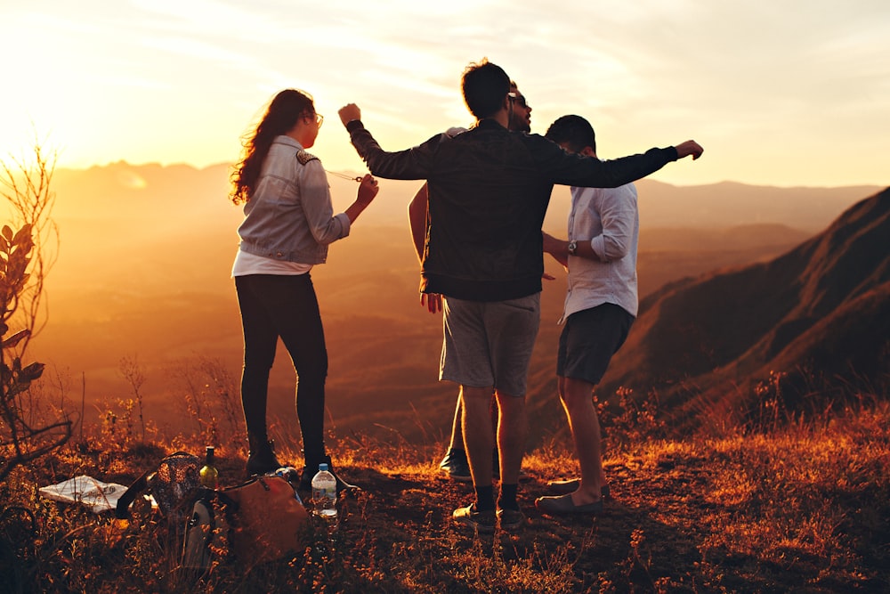 four people standing on edge of mountain