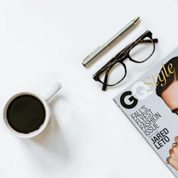 clear eyeglasses with black frame near white ceramic coffee cup
