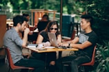 A casual outdoor team meetup in a park with coffee cups and laptops.