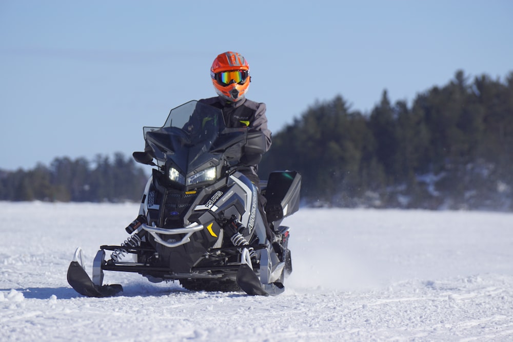 hombre montado en moto de nieve negra