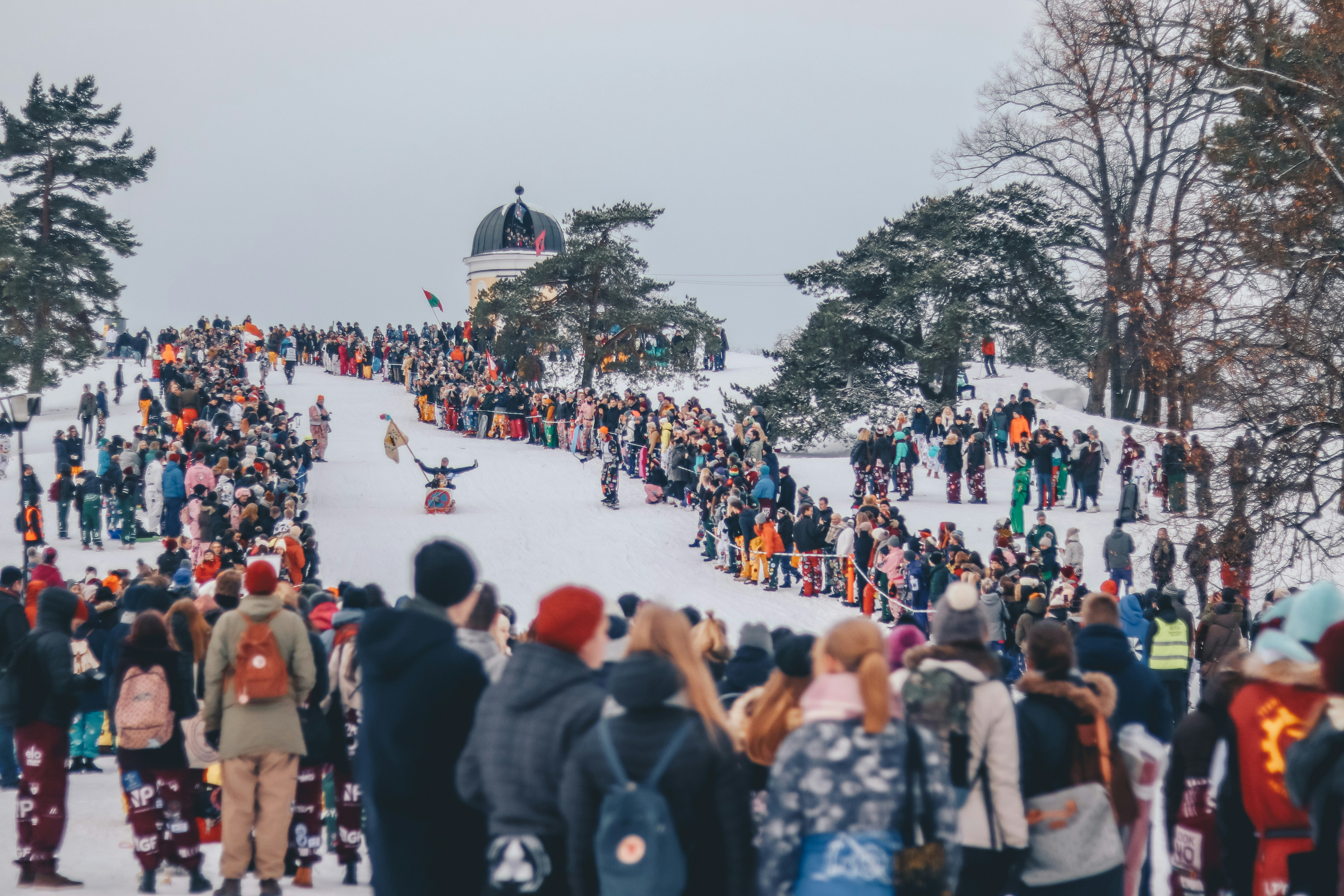 people stands on snow and watches sled race during daytime