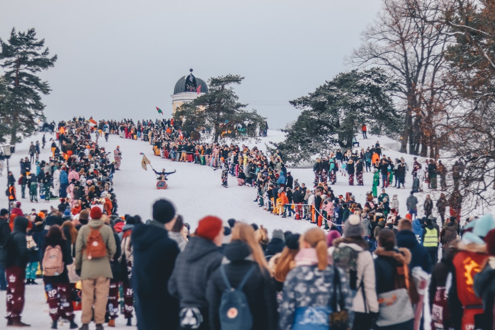 people stands on snow and watches sled race during daytime