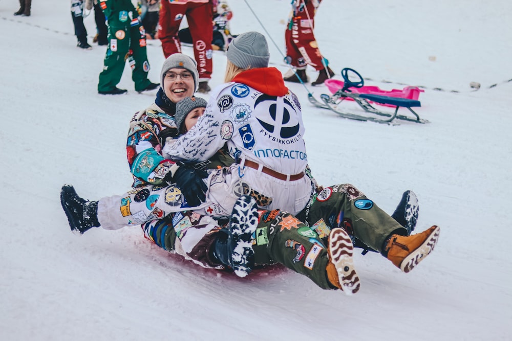 three persons riding on sled