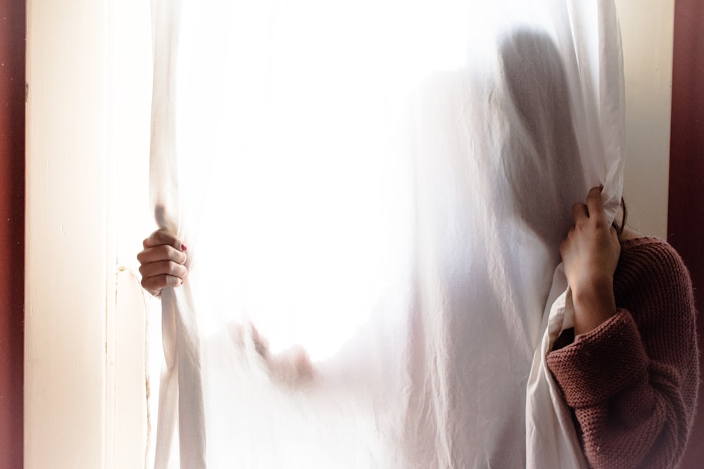 person hiding on white curtain