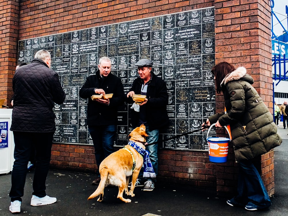 a group of people standing next to a brick wall