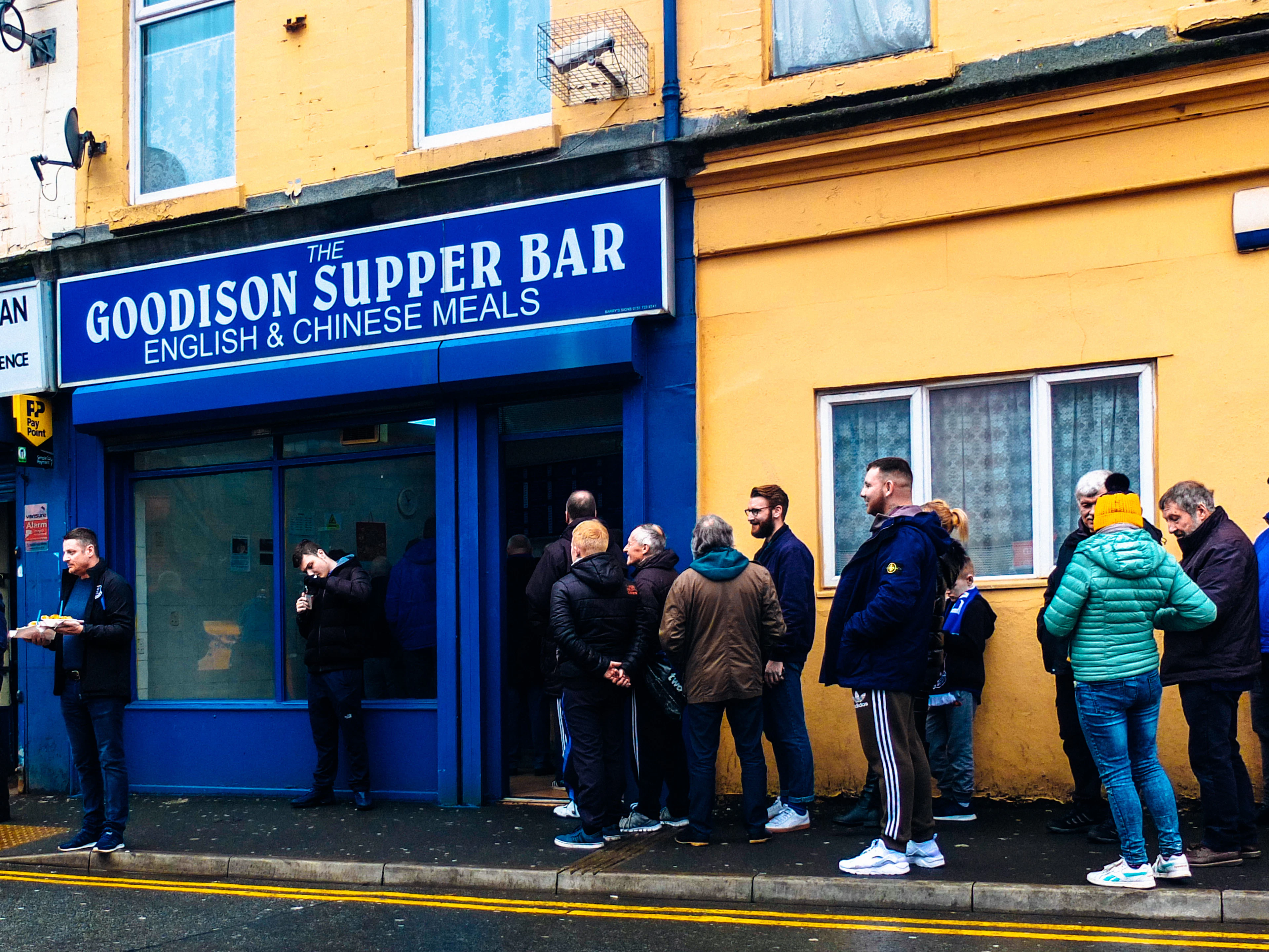 A queue of fans outside the blue-fronted Goodison Supper Bar chip shop near Everton's old stadium.