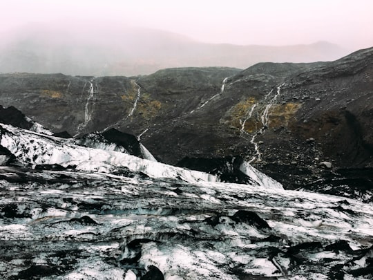 brown hill near gray log at daytime in Sólheimajökull Iceland