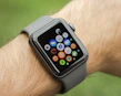 Close-up of a smartwatch on a wrist displaying vibrant app icons against a blurred city background.