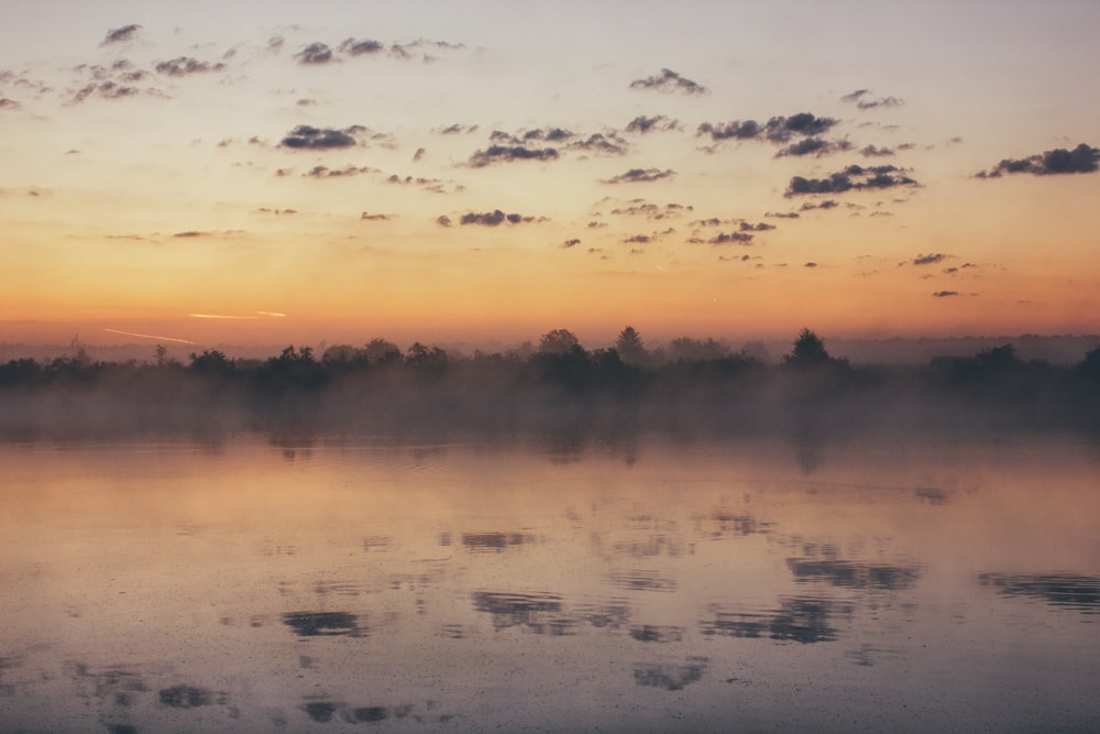 landscape photography of body of water across mountain at sunset