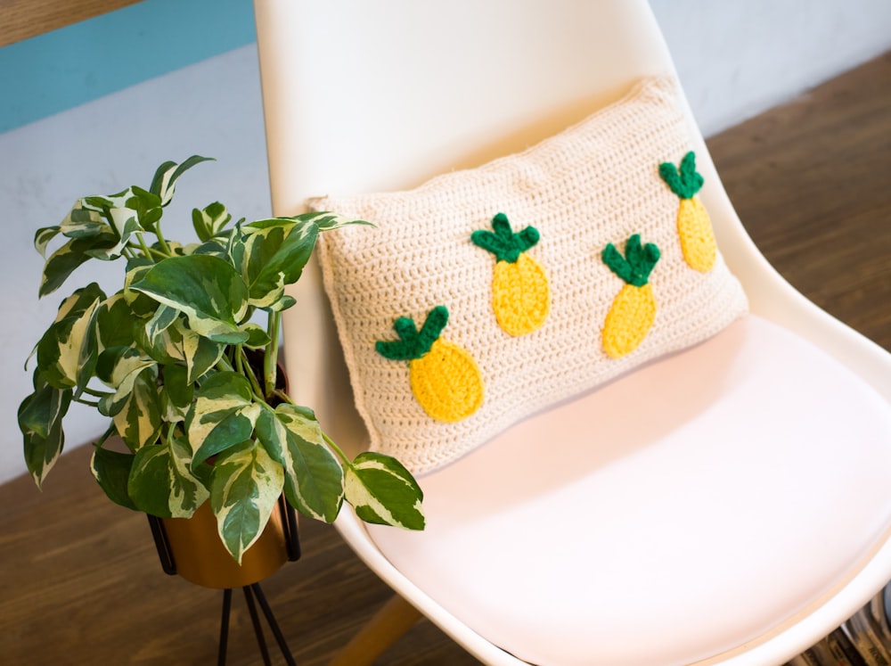 throw pillow on chair beside plant on stand